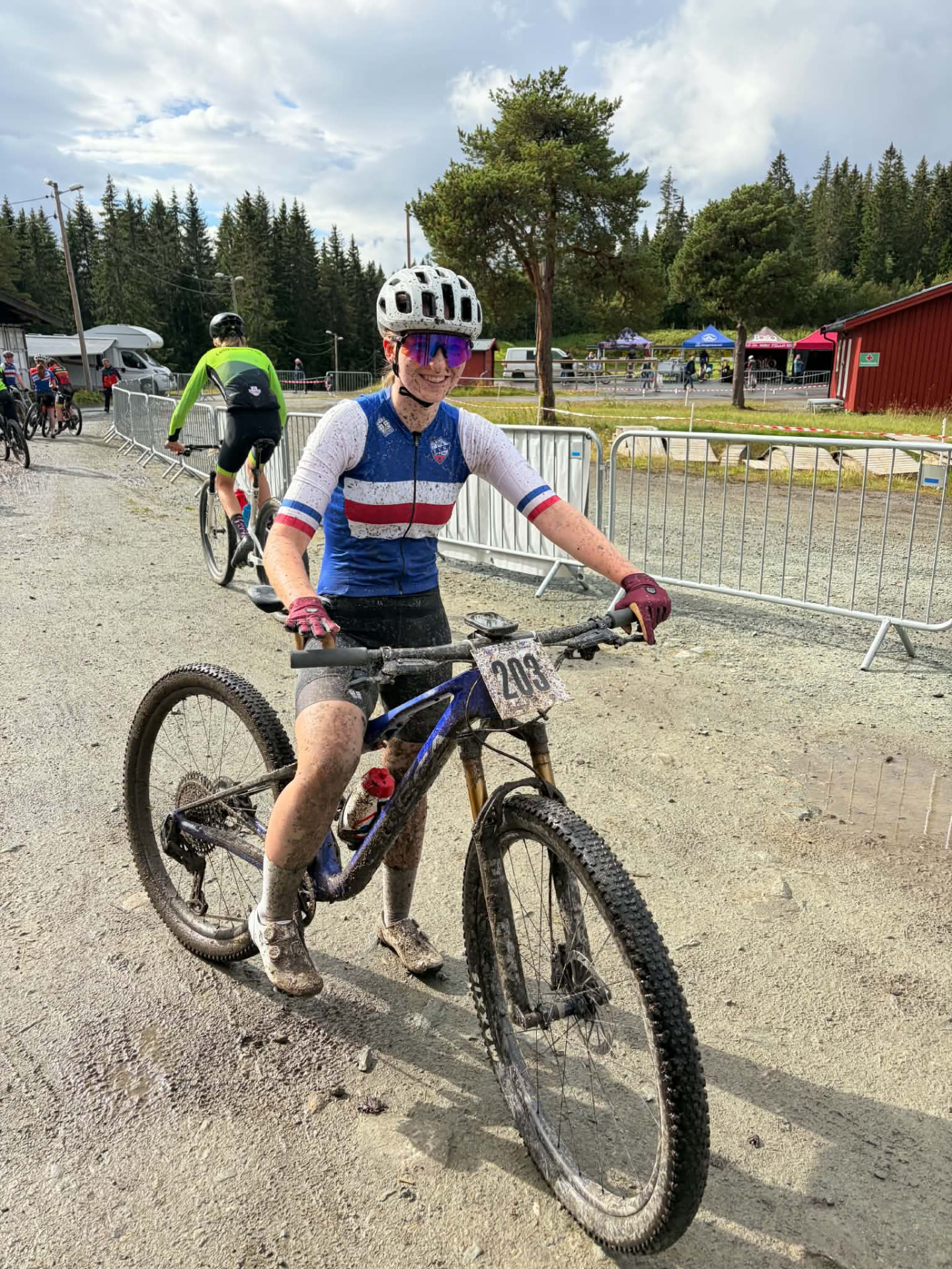 Smilende BSK-løper med sølete sykkel og startnummer 203 etter Norgescup