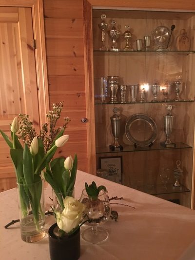 Pokalskap i storstua med blomster på bordet